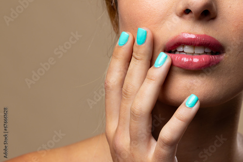 Caucasian woman wearing natural makeup and blue nail polish on beige background, copy space © vectorfusionart