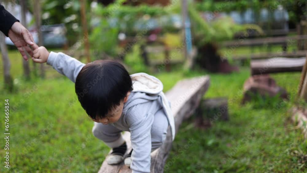 A boy walks on a log keeping balance in the park. A boy walks on a log keeping balance in the park.