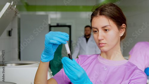 Young attractive female Caucasian doctor-cosmetologist demonstrates blood collection tube with centrifuged blood - separated platelet rich plasma photo