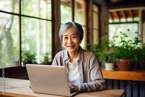 Free Download senior Asian woman working remotely on laptop in seasonal homestay - GFXLoad