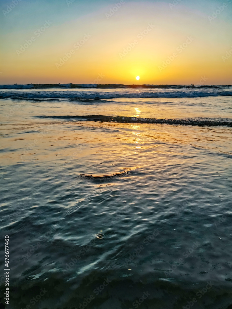 Sunset on Mandrem Beach in Goa, India. Bright and colorful sunset over the Indian Ocean, the Arabian Sea. A tropical beach with yellow sand and a bronze sunset. Sunset on Mandrem Beach in Goa, India. Bright and colorful sunset over the Indian Ocean, the Arabian Sea. A tropical beach with yellow sand and a bronze sunset.