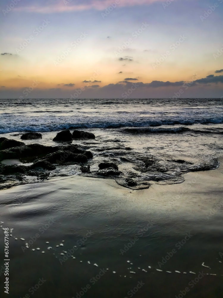 Obraz premium Sunset on Mandrem Beach in Goa, India. Bright and colorful sunset over the Indian Ocean, the Arabian Sea. A tropical beach with yellow sand and a bronze sunset.