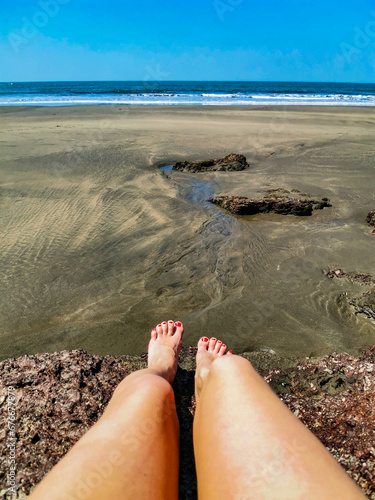 A girl on Mandrem Beach in Goa, India. Bright and colorful view of the Indian Ocean, the Arabian Sea. A tropical beach with yellow sand and coral stones.