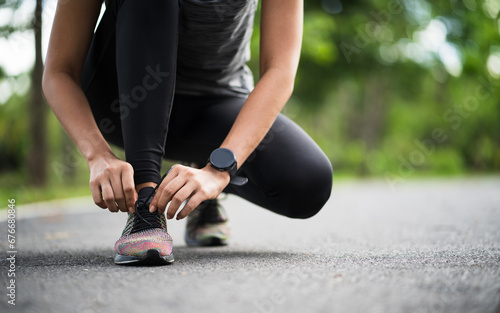 Running shoes runner woman tying laces for autumn run in forest park. Runner trying running shoes getting ready for run. Jogging girl exercise motivation heatlh and fitness.
 photo