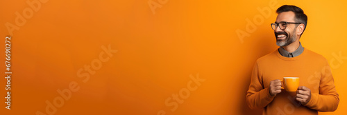 Happy man with cup of coffee on orange background photo