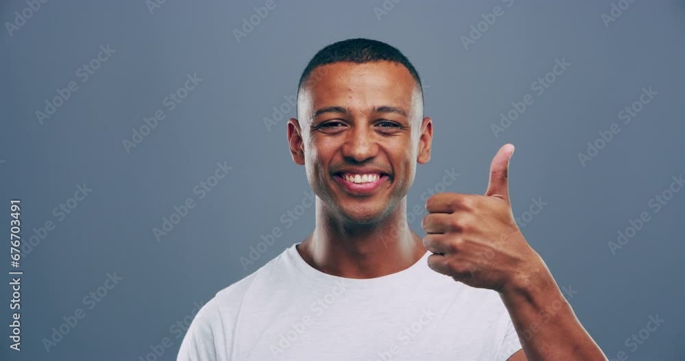 Black man, thumbs up and success, winning or thank you for vote, support or like emoji with smile in studio. Face of student or winner in yes, ok and agreement hands or opportunity on gray background Black man, thumbs up and success, winning or thank you for vote, support or like emoji with smile in studio. Face of student or winner in yes, ok and agreement hands or opportunity on gray background