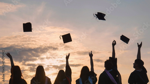 Fotografie Student graduates toss their caps at sunset.