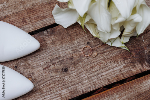 Beautiful wedding accessories  details  bride s set  beige shoes  bouquet of flowers with gold rings on a wooden surface.