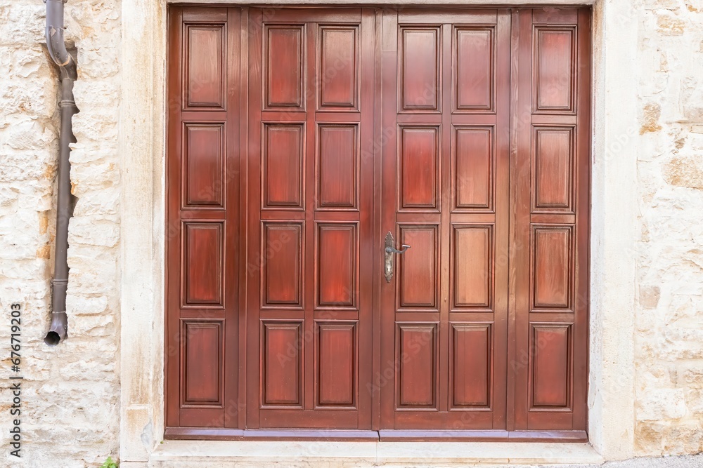 Image of a brown entrance door to a residential building with an antique façade