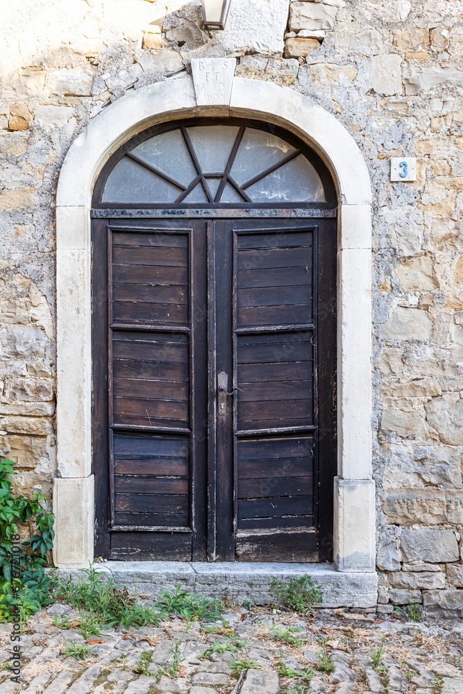 Image of a wooden entrance door to a building with an antique façade Image of a wooden entrance door to a building with an antique façade