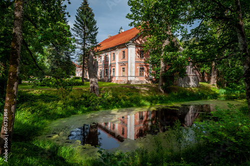 Abandoned Manor House in Kurzeme, Latvia. Stende Manor. View of the manor from the park with reflection in the river. photo