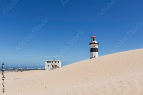 Black and white lighthouse behind a sand dune 