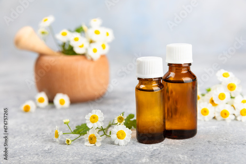 Glass bottle with chamomile essential oil on an old wooden background. Chamomile flowers, close up. Aromatherapy, spa and herbal medicine ingredients. Beauty concept.Copy space. Natural cosmetic