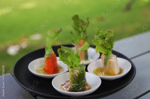 Homemade of fresh vegetable salad roll bite sized and served on small plate with spicy dipping sauce. A healthy appetizer rich in vegetable fiber. Spring rolls Vietnamese with vegetables and shrimps. 