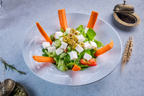 A blate of green salad with cheese and carrots on a gray background photo