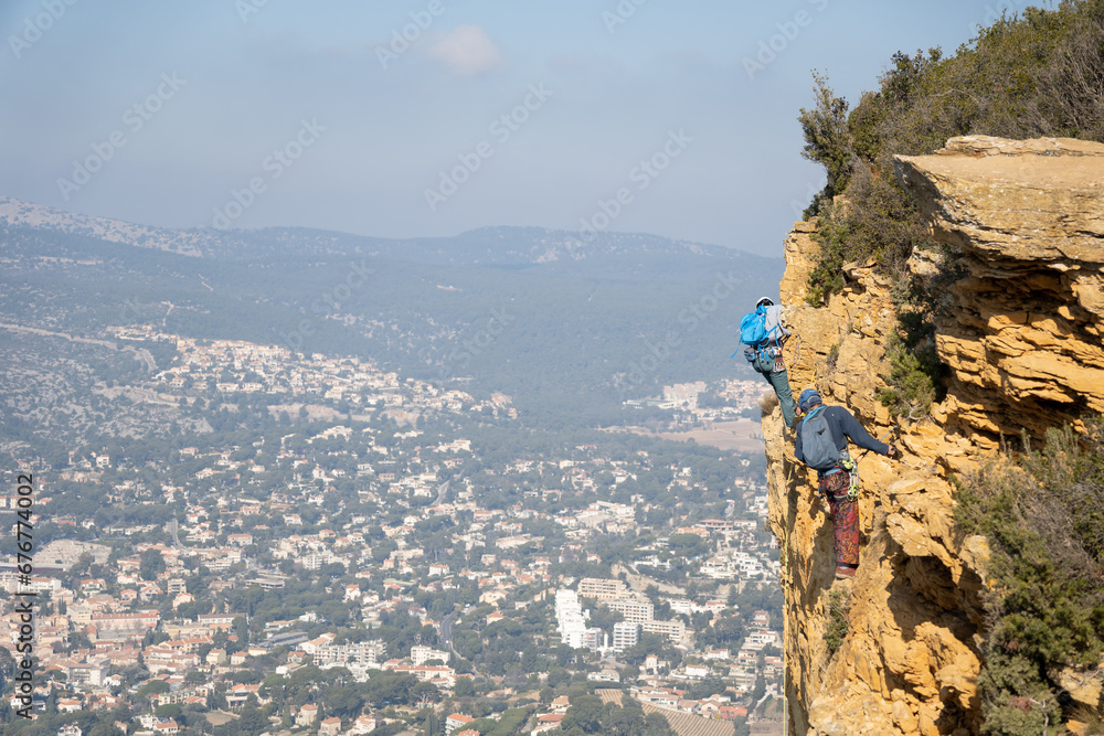 Deux personnes en train de faire de l'escalade sur une falaise avec le vide 