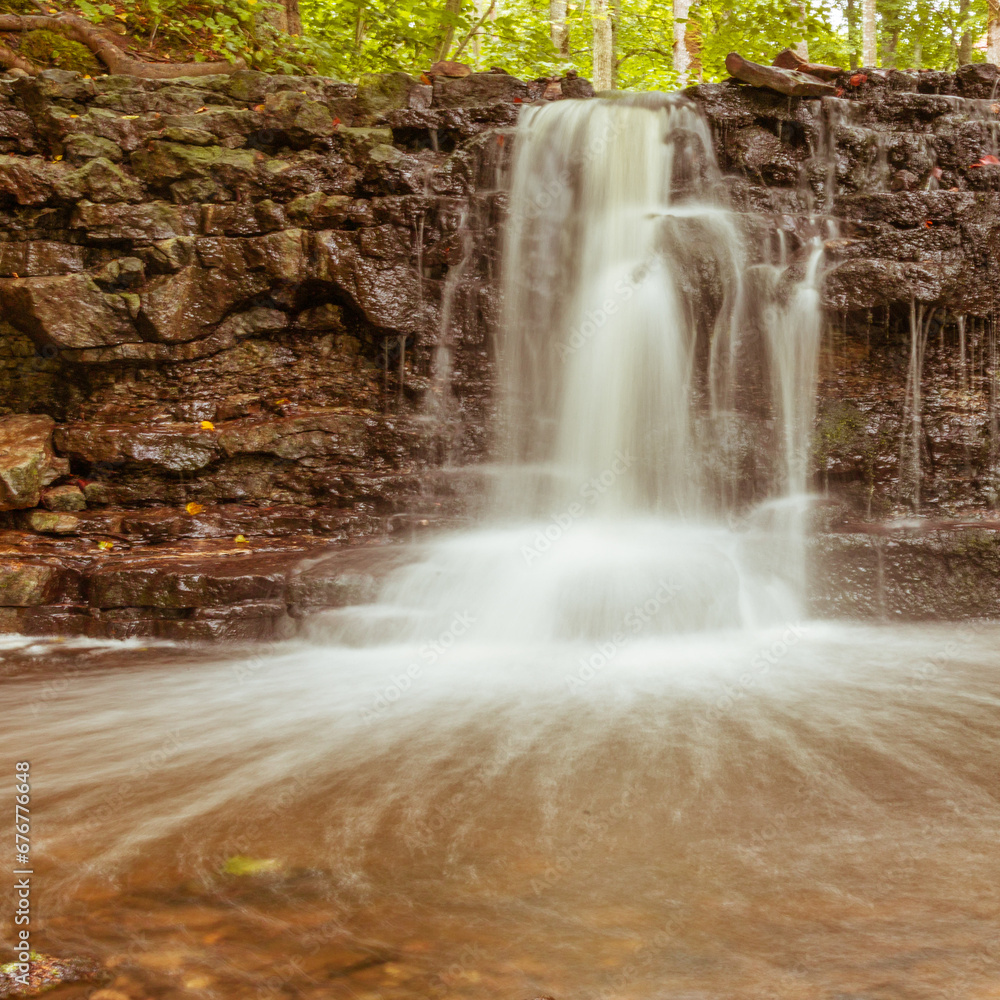 Obraz premium A small waterfall in the middle of the forest between dolomite rocks, long exposure