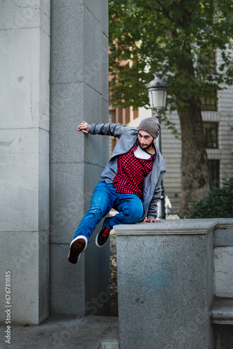 Athletic guy performs parkour on a wall, showcasing urban agility.