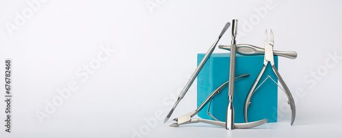 Various beauty tools, spatula, clippers, on a light background with a blue decorative cube.