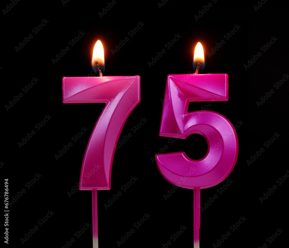 Burning pink birthday candles isolated on black background, number 75. Burning pink birthday candles isolated on black background, number 75.