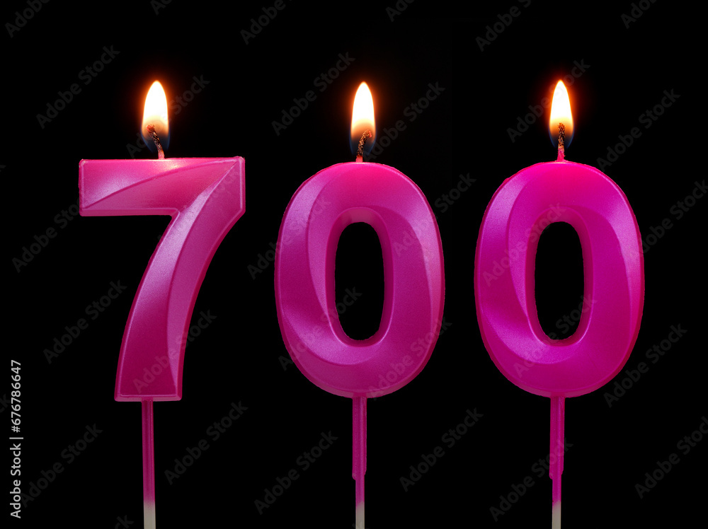 Burning pink birthday candles isolated on black background, number 700. Burning pink birthday candles isolated on black background, number 700.