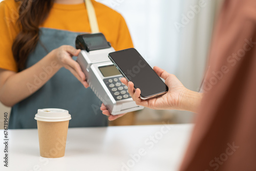 Pay, cashless technology concept, customer using smart mobile phone for payment, paying money to transfer cashless at cafe shop to buy breakfast, holding wireless bank machine at counter cashier.