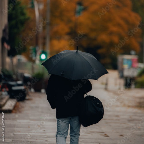 City Street Sheltering: Person Walking with Umbrella in Rainy Autumn Monsoon