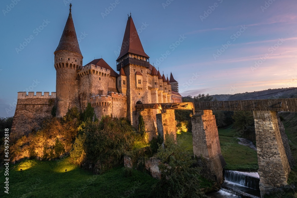 an old castle with a bridge at dusk and the sky is blue: Corvin Castle Hunedoara Romania