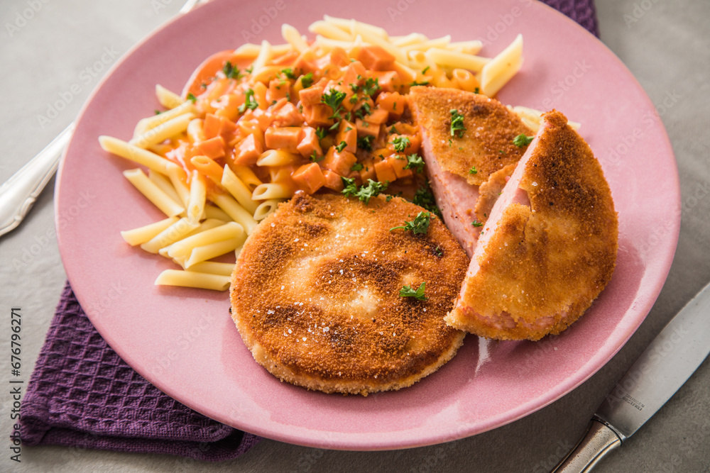 Jägerschnitzel nach DDR GDR Rezept mit Jagdwurst paniert, Makkaroni Penne Nudeln, Tomatensoße, Petersilie mit pink rosa Teller, Besteck, lila Serviette und Marmor Hintergrund Jägerschnitzel nach DDR GDR Rezept mit Jagdwurst paniert, Makkaroni Penne Nudeln, Tomatensoße, Petersilie mit pink rosa Teller, Besteck, lila Serviette und Marmor Hintergrund