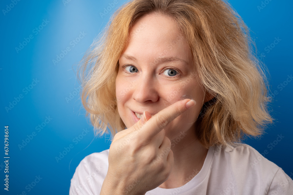 Fototapeta premium woman putting on contact eye lenses on blue background