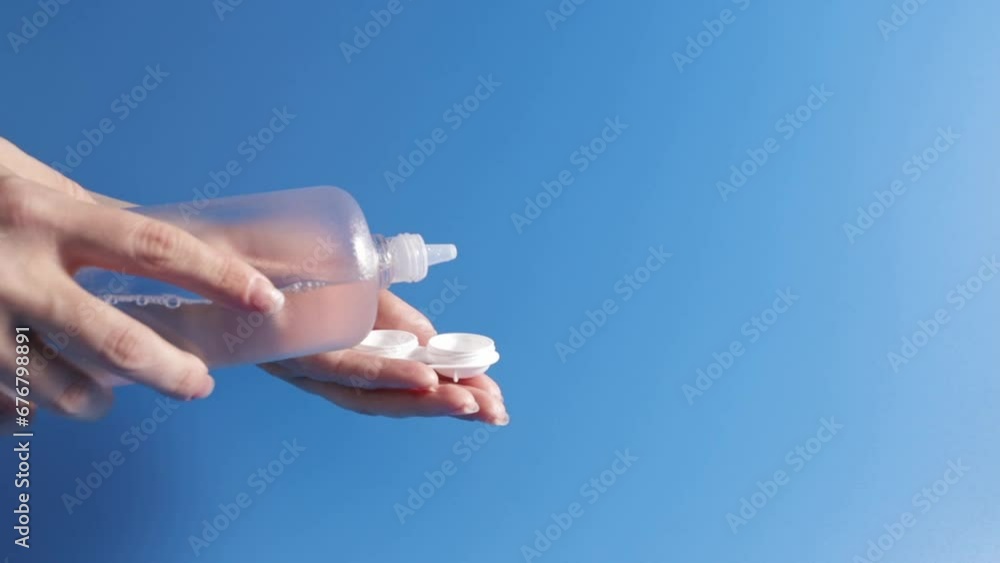 lens solution, female hands pouring cleaning liquid from a bottle into a contact lens case on a blue background, Ophthalmology and eye care, optical hygiene lens solution, female hands pouring cleaning liquid from a bottle into a contact lens case on a blue background, Ophthalmology and eye care, optical hygiene