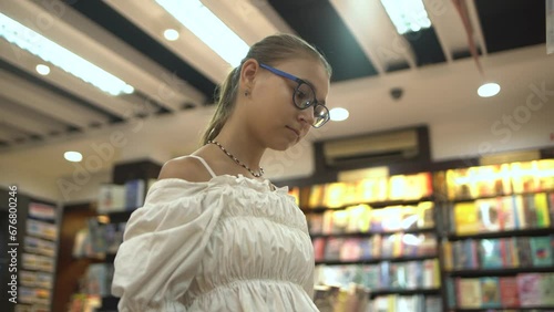 Close-up of caucasian teenage girl look at books on bookshelves in a bookstore.