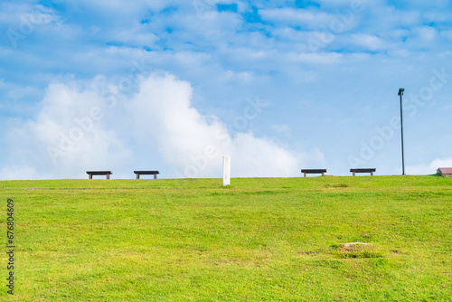 Fototapeta Naklejka Na Ścianę i Meble -  Garden bench with Green meadows with blue sky and clouds background.