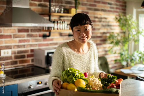 Happy woman preparing fresh vegetables in the kitchen looking at camera © Vorda Berge