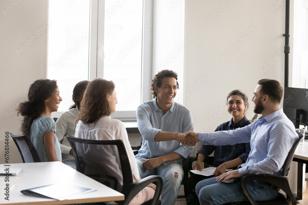 Cheerful confident business colleagues men shaking hands with recognition, acknowledgement, congrats on success, thanking, smiling, laughing. Group mates giving greeting handshake on therapy meeting