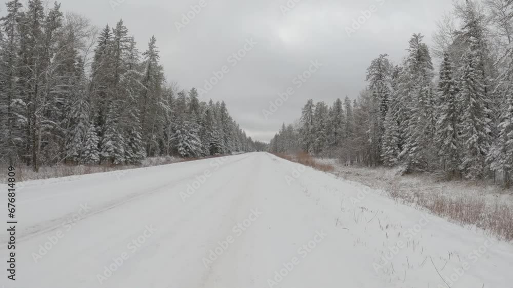 POV from the front of a vehicle driving along a rural road and meeting a large logging truck that is full of logs. The road and trees are covered with snow.
POV from the front of a vehicle driving along a rural road and meeting a large logging truck that is full of logs. The road and trees are covered with snow.