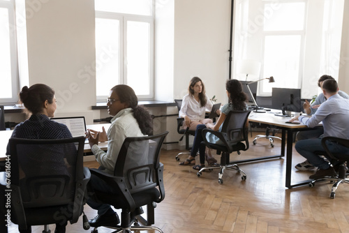 Pairs of diverse business colleagues working in modern office space, sitting at workplace desks, discussing project tasks, brainstorming, networking, cooperating on tasks, meeting for teamwork photo
