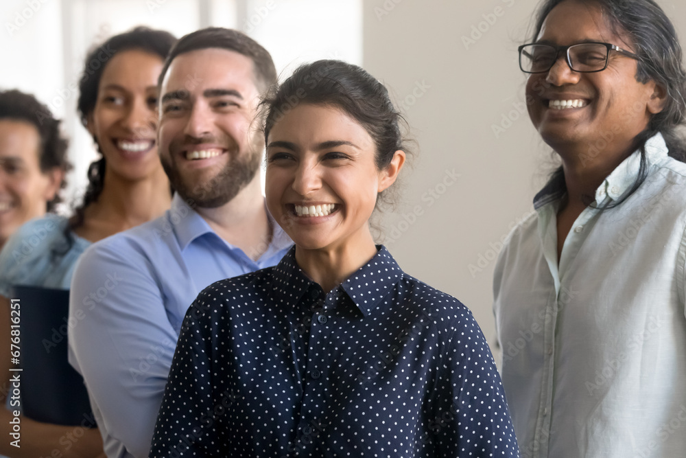 Excited cheerful diverse team of department employees standing together, looking away with happy toothy smiles. Successful business colleagues posing for camera, celebrating good startup Excited cheerful diverse team of department employees standing together, looking away with happy toothy smiles. Successful business colleagues posing for camera, celebrating good startup