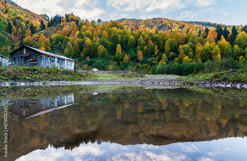 Reflection of trees and shed in the water in autumn colors