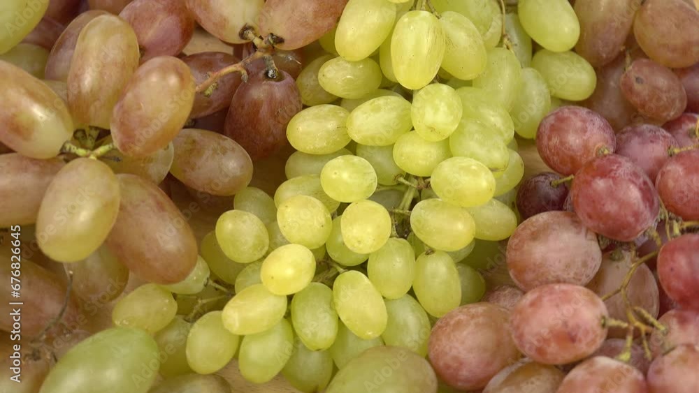Large bunches of ripe grape of various varieties lies on a table, background