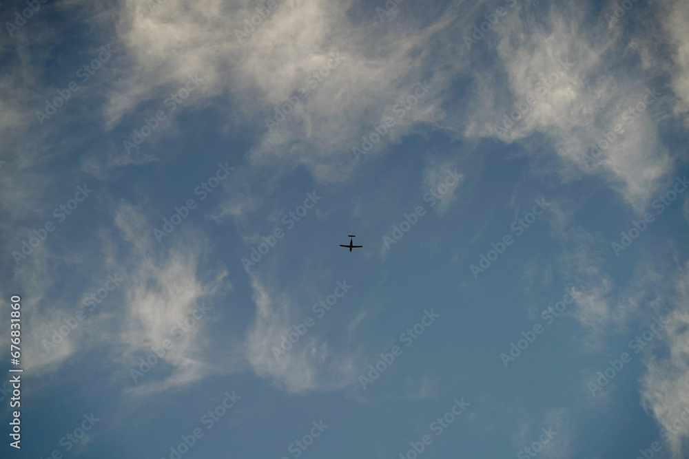 small airplane flying on the blue cloudy sky