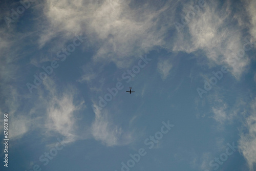 small airplane flying on the blue cloudy sky