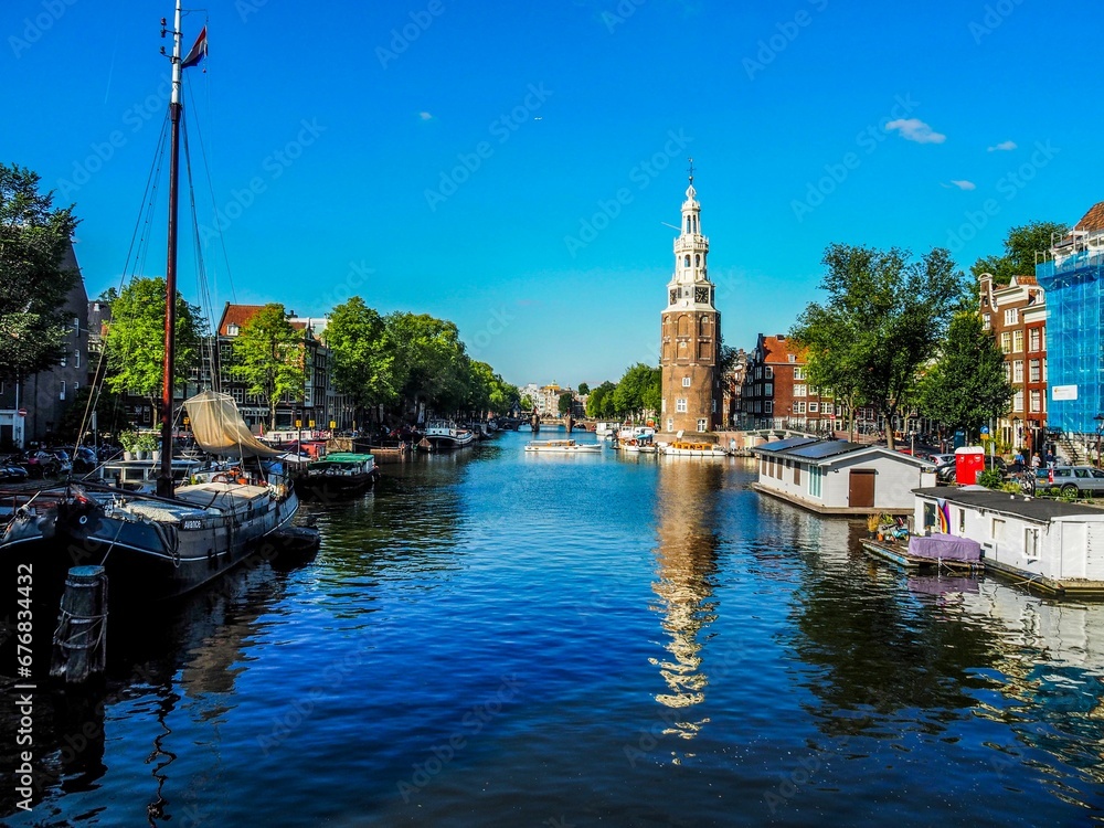 Montelbaanstoren Tower on bank of the Oudeschans canal on a sunny day in Amsterdam, Netherlands