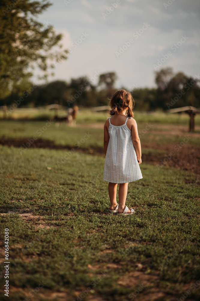 little girl standing back in the field little girl standing back in the field