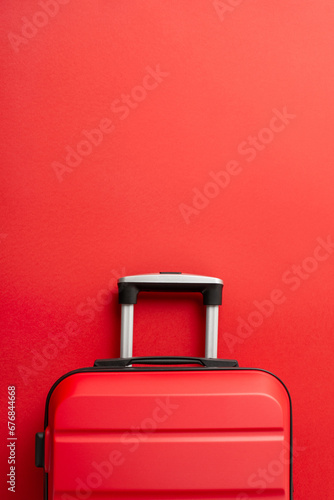 Festive adventure concept. Top view vertical photograph of trendy red suitcase on a red background, offering space for text or promotion
