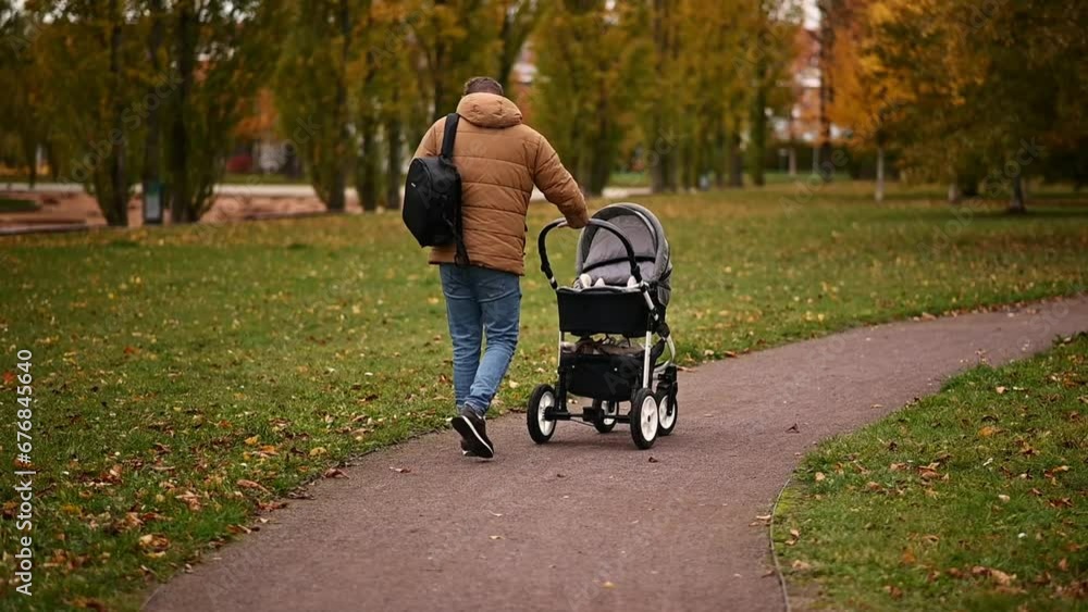 Father with little son walking in baby stroller in autumnal park Father with little son walking in baby stroller in autumnal park