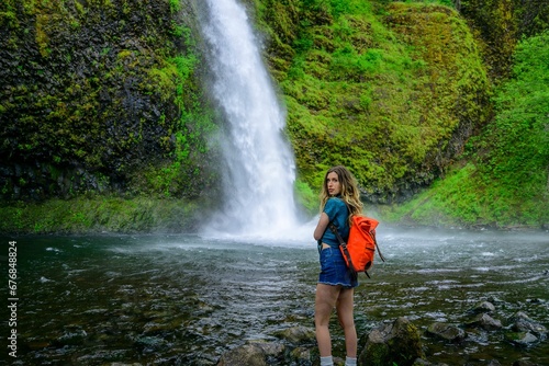 Attractive Caucasian woman standing against the Multnomah Falls in Oregon, Portland, USA