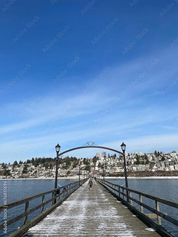 Vertical shot of a person on wooden White Rock Pier in Canada