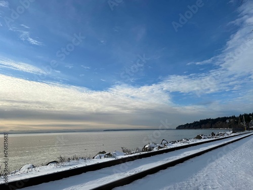Scenic view of white snowy lakeshore under blue cloudy sky