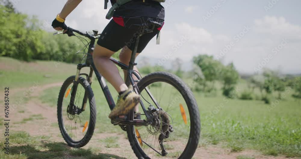 Man riding a mountainbike down a dusty path with scenic countryside views. Dirtroad next to a green meadow. Man riding a mountainbike down a dusty path with scenic countryside views. Dirtroad next to a green meadow.